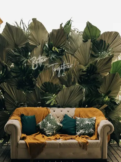 Personal touches make a wedding special. We designed this cozy seating area with a custom "Better Together" neon sign against a backdrop of tropical leaves, perfect for a modern Mehendi or pre-wedding photoshoot.