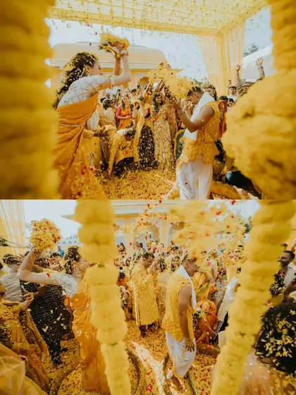 A dynamic shot from within the marigold decor, capturing the couple being showered with an explosion of yellow petals.