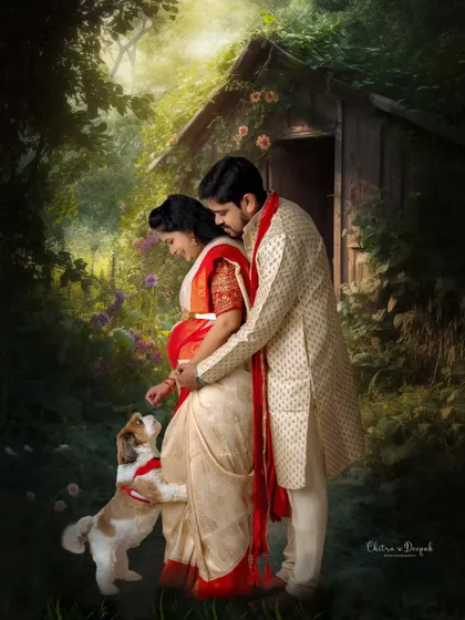 An artistic and romantic maternity portrait of a couple in traditional Indian attire, sharing a tender moment with their beloved pet in a magical, painterly forest setting. This highlights our ability to create fine art pieces and include furry family members.