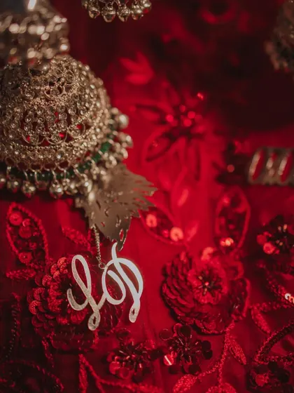 A close-up detail shot of a custom-made kalire charm with the couple's initials, showcasing the personalized elements of the wedding.