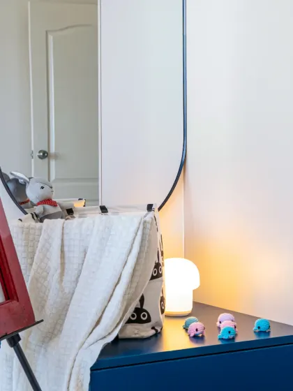 The little details are what complete a design. In this kids' room, the small toys on the dresser and the child's artwork on the easel are not clutter; they are the elements that bring the space to life and make it a real home.