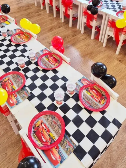 The kids' tables at the Cars party, complete with checkered runners, themed plates and cups, and balloon decorations.