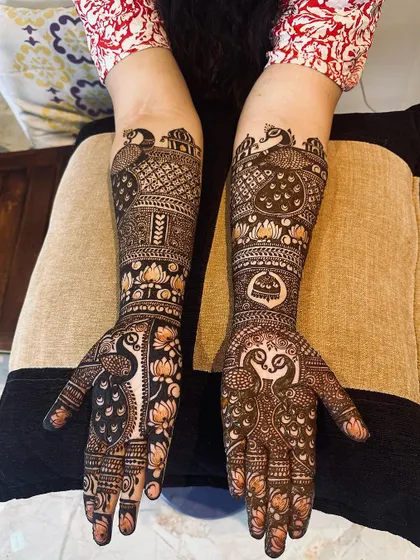 A beautiful example of symmetrical design, with peacocks and architectural elements mirrored on both hands. The negative space around the main motifs makes them stand out.