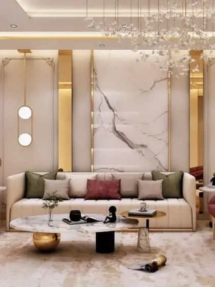 This living room is the epitome of luxury, featuring a plush cream sofa accented with deep red armchairs and gold detailing. The design incorporates a marble feature wall, ornate pendant lighting, and classic wall molding to create a space of timeless sophistication.
