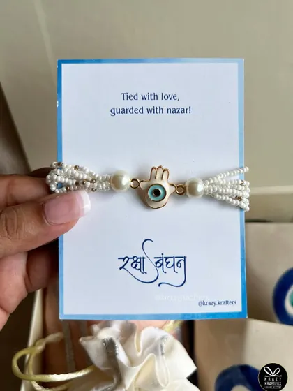 "Tied with love, guarded with nazar!" A close-up of the beautiful evil eye hamsa rakhi, perfect for protecting your sibling.