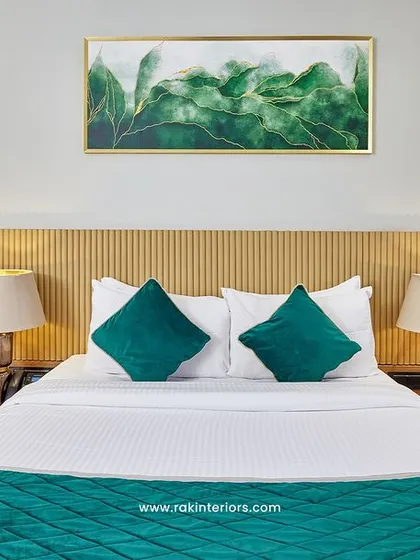 A close-up of a hotel bedroom showcasing the interplay of textures and colors. The custom wooden headboard, plush teal bedding, and warm side lighting come together to create a welcoming and stylish space.