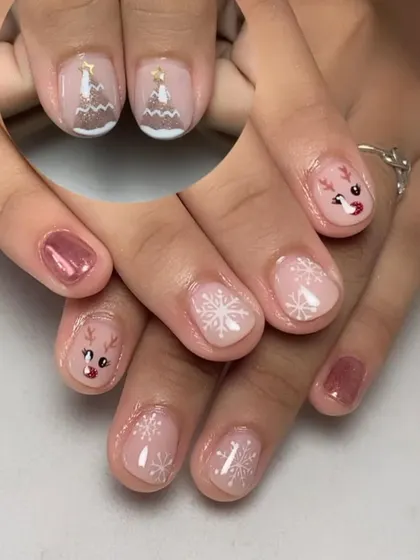 A soft and sweet Christmas manicure with hand-painted reindeer, snowflakes, and Christmas trees on a sheer pink base.