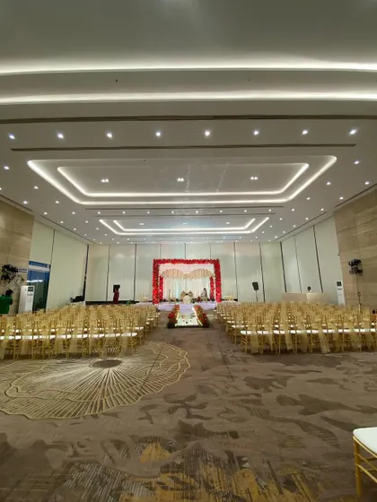 A wide view of the wedding hall, showing the grand scale of the red and white mandap. The seating is perfectly arranged to give every guest a clear view of the ceremony.