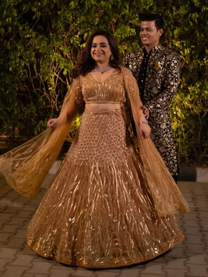 Our bride Shivali enjoying the best moments of her Sangeet in this gorgeous lehenga with an orange undertone and gold sequin work.