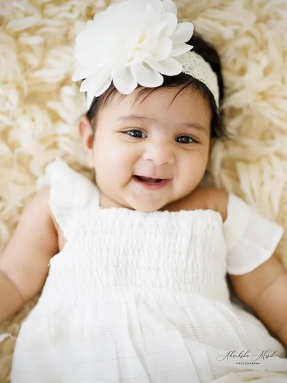 A happy and alert baby girl, smiling for the camera. I love capturing these moments of connection, where their little personality starts to shine through.