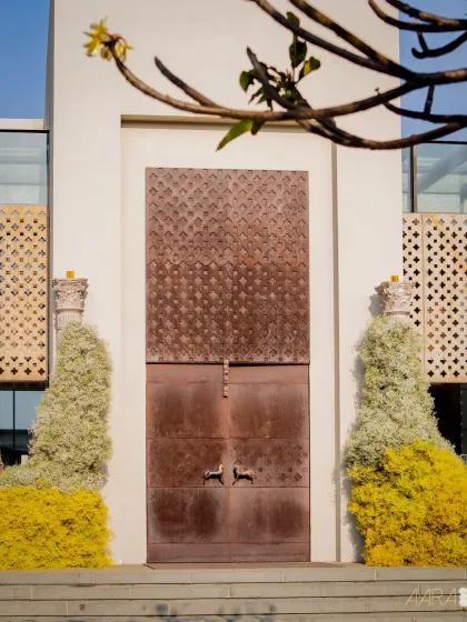 The entrance to the 'Golden Origami Garden', where modern architecture is softened with vibrant yellow and white floral installations. The design is a beautiful blend of artistry and nature.