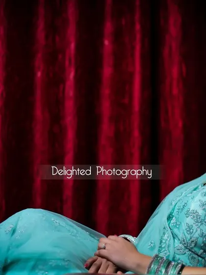 An elegant, posed portrait of a woman in a lovely light blue dress, seated against a rich red curtain, creating a classic and sophisticated look.