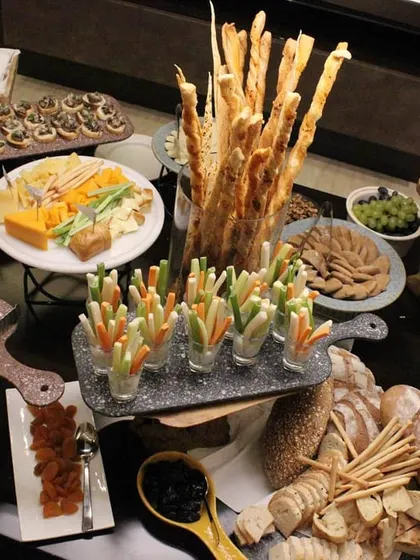An overhead view of a grazing table we created for a private event. It features an abundant selection of breads, grissini, vegetable crudités, cheese boards, and various dips like hummus.