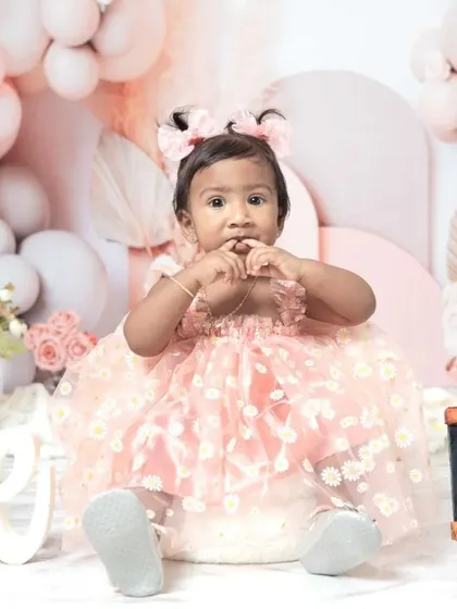 A sweet one-year-old girl enjoying her pink-themed cake smash session. I love capturing these close-ups of their frosting-covered fingers and happy faces.