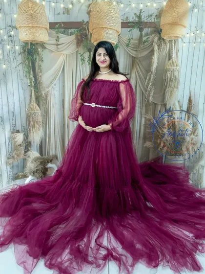 A full-length portrait of a mom-to-be in a beautiful magenta gown, taken in our boho studio.