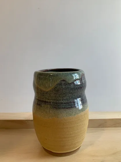 A rustic, hand-thrown vase with a drippy, multi-layered glaze. The organic shape and rich colors give it a lot of character.