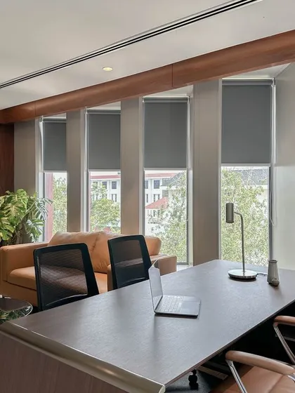 An executive office that combines function with comfort. The space is organized around a large wooden desk and features a dedicated lounge area, custom full-height walnut cabinetry, and large windows with automated blinds for natural light control.