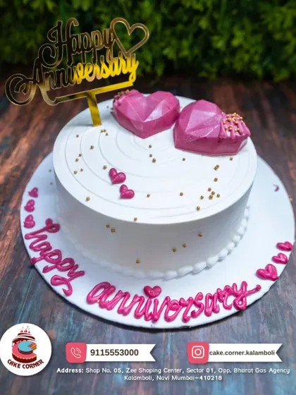A sweet anniversary cake with two geometric pink hearts on top. The simple white design with pink lettering is modern and full of love.