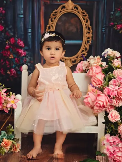 This little princess is sitting confidently on her bench. The vintage-inspired props and floral background make for a truly enchanting portrait.