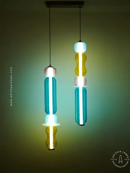 Add a playful pop of color with these kinetic sculpture pendants. Featuring stacked segments of hand-blown glass in teal, amber, and blush, these lights are a fun and artistic addition to any creative space.