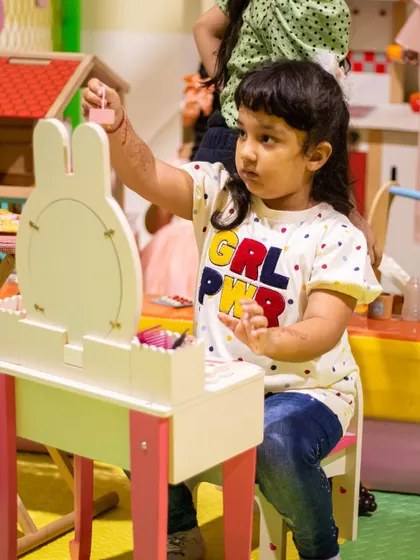 Girl power! This little one is getting ready at our play vanity, a popular spot for imaginative role-playing.