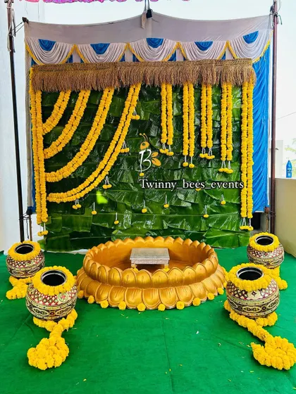 This is another variation of our banana leaf backdrop, designed for a naming ceremony. The setup includes a large lotus-shaped basin, traditional pots (kalasha), and hanging marigold garlands, creating a complete ritual space.