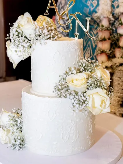 A close-up of the anniversary cake at the event. The delicate lace stencil and fresh flowers create such a classic and elegant look.