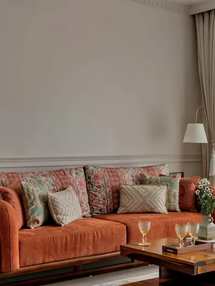 This living room balances simplicity and vibrancy. The earthy terracotta sofa, adorned with patterned cushions, is contrasted by a bright yellow accent chair, creating a space that is both warm and cheerful.