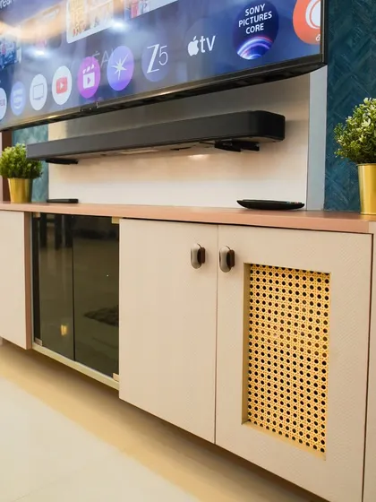 A close-up of a custom TV console featuring a blend of light-colored laminate, glass, and cane webbing on the cabinet doors. This piece combines modern design with natural textures for a unique look.