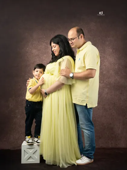A tender moment between parents and their son, all focused on the new life on the way. Coordinated yellow outfits bring a sunny and happy feel to this maternity portrait.
