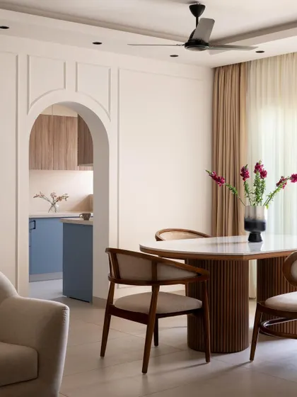 This view from the dining area into the kitchen highlights an open-concept living design. The fluted wood dining table complements the kitchen's textures, creating a cohesive and inviting space for family gatherings.