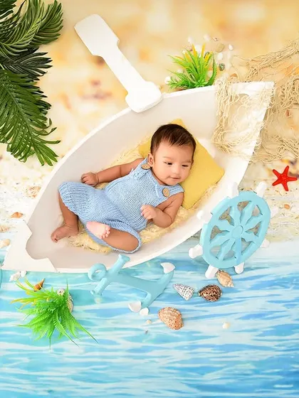 A tiny sailor adrift on a calm sea. This creative newborn setup uses a boat prop and a beachy backdrop to create a sweet and imaginative scene.