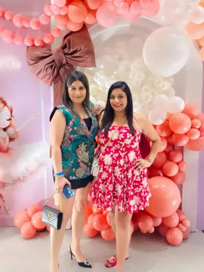 Two guests smiling for a photo in front of the stunning balloon decor.