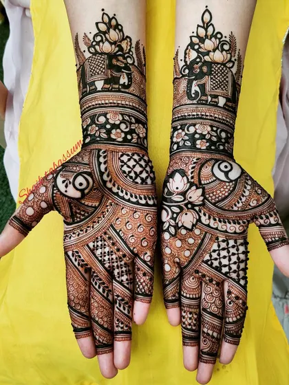 A striking design combining bold, dark henna application with delicate patterns. It features elephant motifs at the top and a mix of floral and geometric elements.