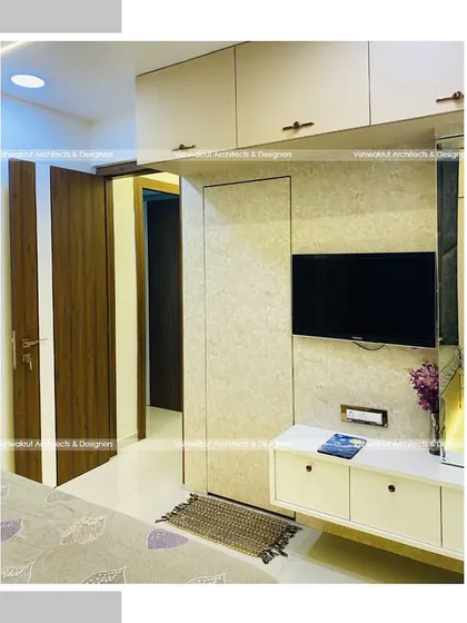 A view of the master bedroom in Majestic Villa, showing the TV unit and dressing table integrated into the wardrobe wall. This creates a seamless and clutter-free look.