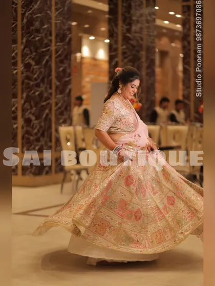 A bride's mami twirling in a beautiful pastel pink and cream lehenga. The intricate embroidery and soft colors make it a graceful choice for a family wedding.