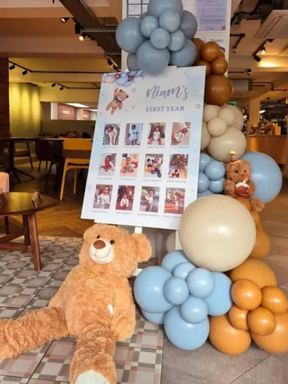 To complement the main decor, I can create smaller themed elements like this "First Year" milestone photo board, beautifully framed with matching balloons and a teddy bear.