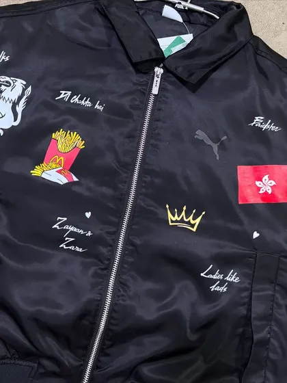 A custom-painted Puma bomber jacket with various personal symbols and text for a client.