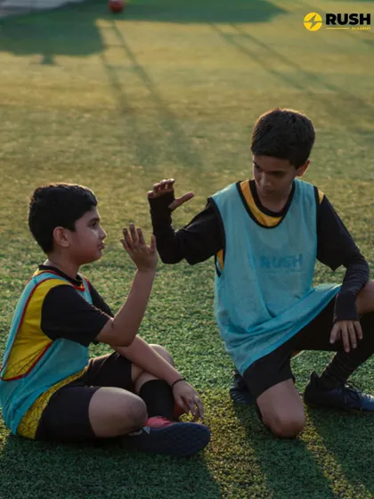 Two players take a break on the grass, sharing a conversation. Friendships formed on the pitch often last a lifetime.