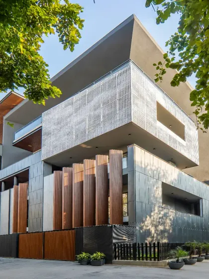 This facade in Sushant Lok, Gurgaon, is a study in volumes and materials. The design features a unique tapered projection, aluminum louvers, and textured tiles, creating a visually compelling composition that plays with light and shadow.