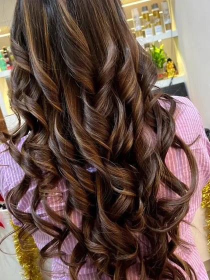 Here, you can see a close-up of a chocolate brown balayage with defined curls. This styling is great for showing how the highlights and lowlights wrap around each curl, creating a dynamic, textured look.