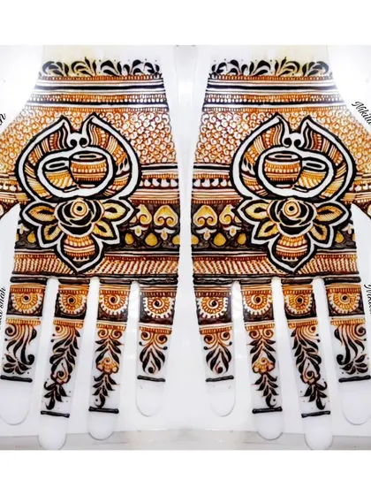 This design plays with perspective. When viewed upright, it appears as a floral pattern, but when you turn it upside down, two sacred Kalash pots are revealed. It's a creative twist on a traditional bridal palm design.