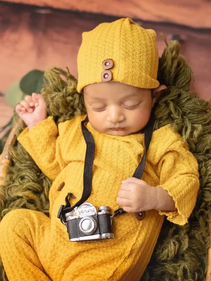Say cheese. This little one is ready for his close-up, dressed as a tiny photographer with a miniature camera prop.