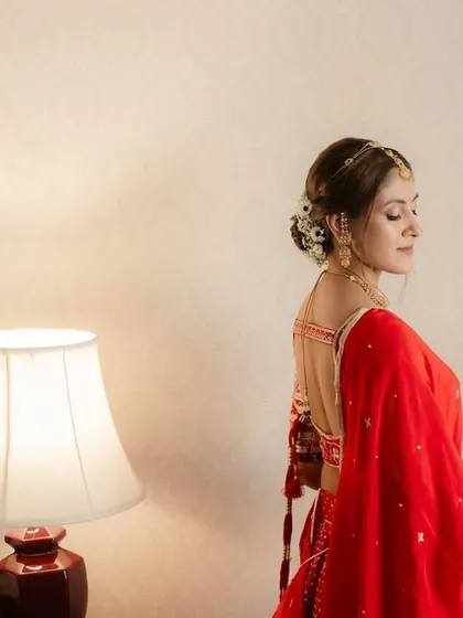 A beautiful shot showcasing the elegant bridal bun adorned with flowers. The clean hairstyle complements the detailed makeup and traditional attire perfectly.