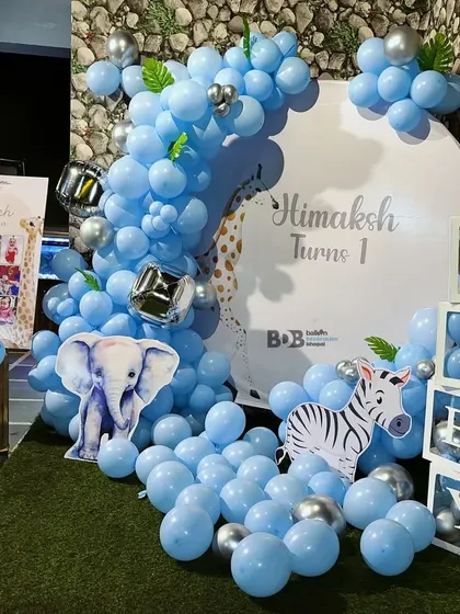 A blue and silver animal-themed first birthday with elephant and zebra cutouts and 'BABY' blocks.