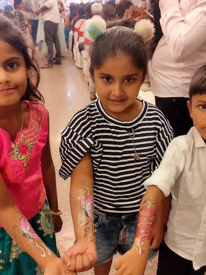 Happy kids showing off their glittery arm paintings at a party.