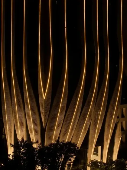 The base of the tower at night, where the illuminated strokes create a dynamic pattern of light and shadow on the ground.