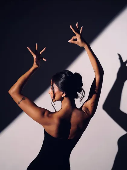 A study of form and shadow, with intricate hand gestures creating a dynamic shape against the light.