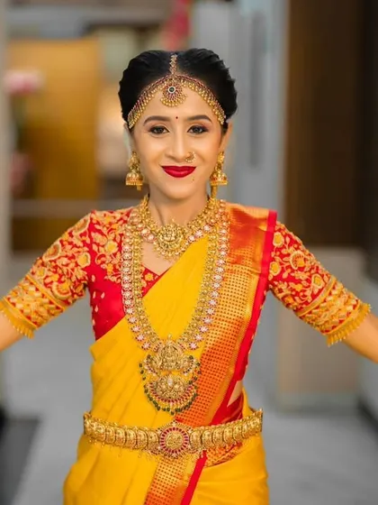 The classic combination of yellow and red is a favorite for a reason. This bride looks absolutely radiant for her muhurtham in a traditional yellow Kanjeevaram silk saree with a richly embroidered red blouse.