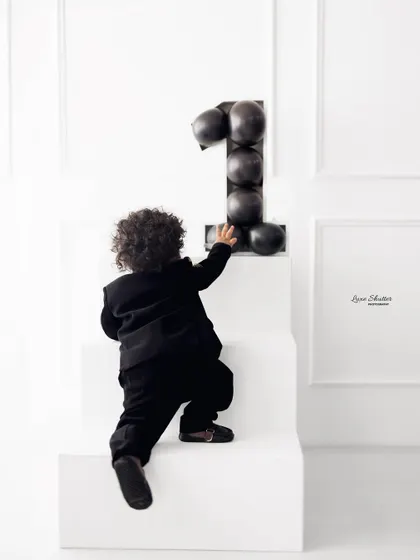 A candid moment from the minimalist first birthday shoot, capturing the little one's curiosity as he reaches for the number one.